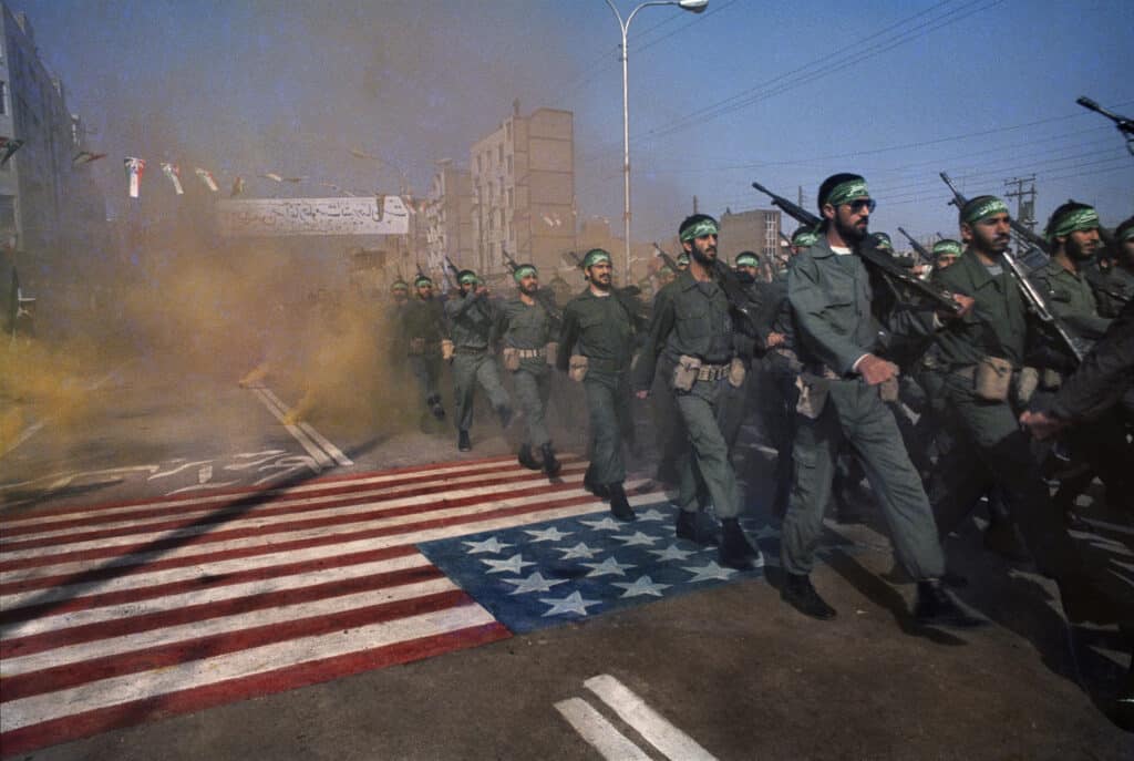 Pasdaran march over a US flag in Ahwaz, in 1983, on the 3rd anniversary of the Iranian revolution © Manoocher Deghati