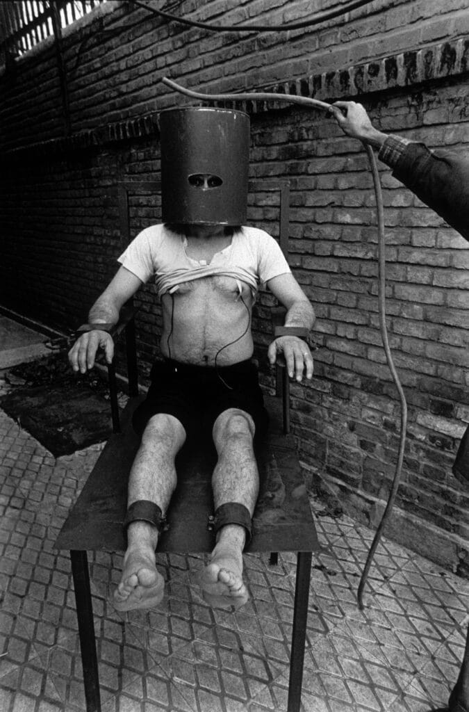 A former political prisoner shows how he was tortured on this torture chair called "Apollo", 1980 © Manoocher Deghati