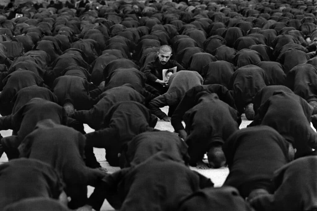 Iraqi prisoners of war are forced to pray with a portrait of Khomeini. One prisoner refused to pray, 1982 © Manoocher Deghati