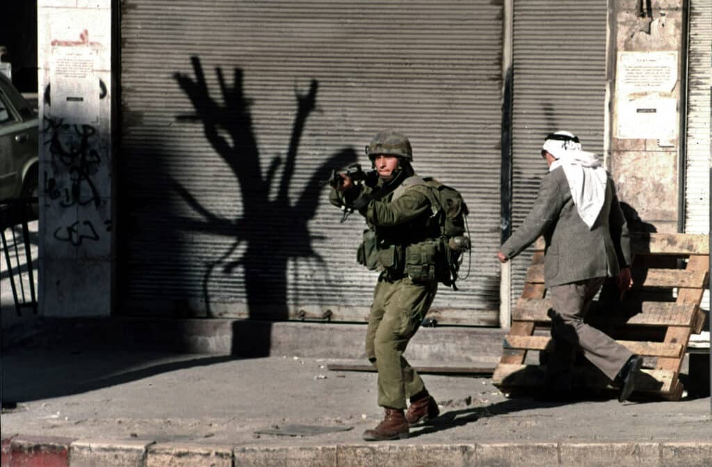 An Israeli soldier aims at demonstrators in Nablus, West Bank, Palestine, November 15, 1995, while hundreds of Palestinians throw stones at Israeli soldiers to celebrate the 7th anniversary of Palestinian "Independence Day" declared so by Yassir Arafat © Manoocher Deghati