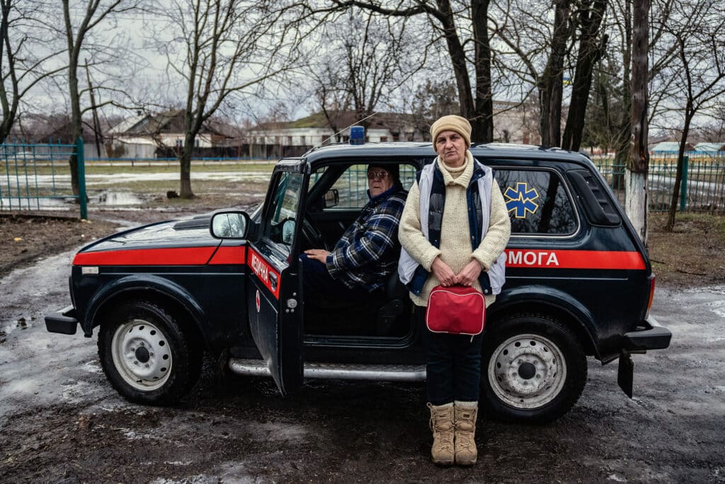 The Last Nurse on the Front Line. Trokhizbenka, Ukraine, February 8 and 9, 2022. © Timothy Fadek Vova drives a Lada Niva, a 4x4 Russian car that he and Lilia use to visit patients at home. Lilia Schwez lives in the eastern Ukrainian village of Trokhizbenka, on the front line with Russian-backed separatists. Her house is so close to the line of control, it can been seen from her back yard and the military checkpoint is a few yards from her front door. Since the war began in 2014, Lilia has seen her sister, who lives on the separatist side, only twice in 8 years. She has not seen her friends at all. She works in an under-staffed and under-funded clinic which serves five villages with a total of mostly elderly 1,365 residents. There is a dentist chair in one room, but there hasn’t been a dentist in years. Another room is for OB-GYN, but the doctor works only one day every week or two. The nearest hospital, in Severodonetsk, is an hour and a half away. So Lilia does housecalls. Vova drives her to her appointments. Trokhizbenka was a weekend getaway destination for urban dwellers. Small, dacha-type houses are everywhere. Before the war, the village was a relaxing place where people could do some gardening or just sit in the back yard to take in the fresh forest air. Lilia and her husband Vova moved from the nearby city Luhansk 15 years ago. “We planned to retire here.” Trokhizbenka is a village in the Luhansk area of eastern Ukraine, on the front line opposite the separatists of the LPR (Luhansk People’s Republic.)