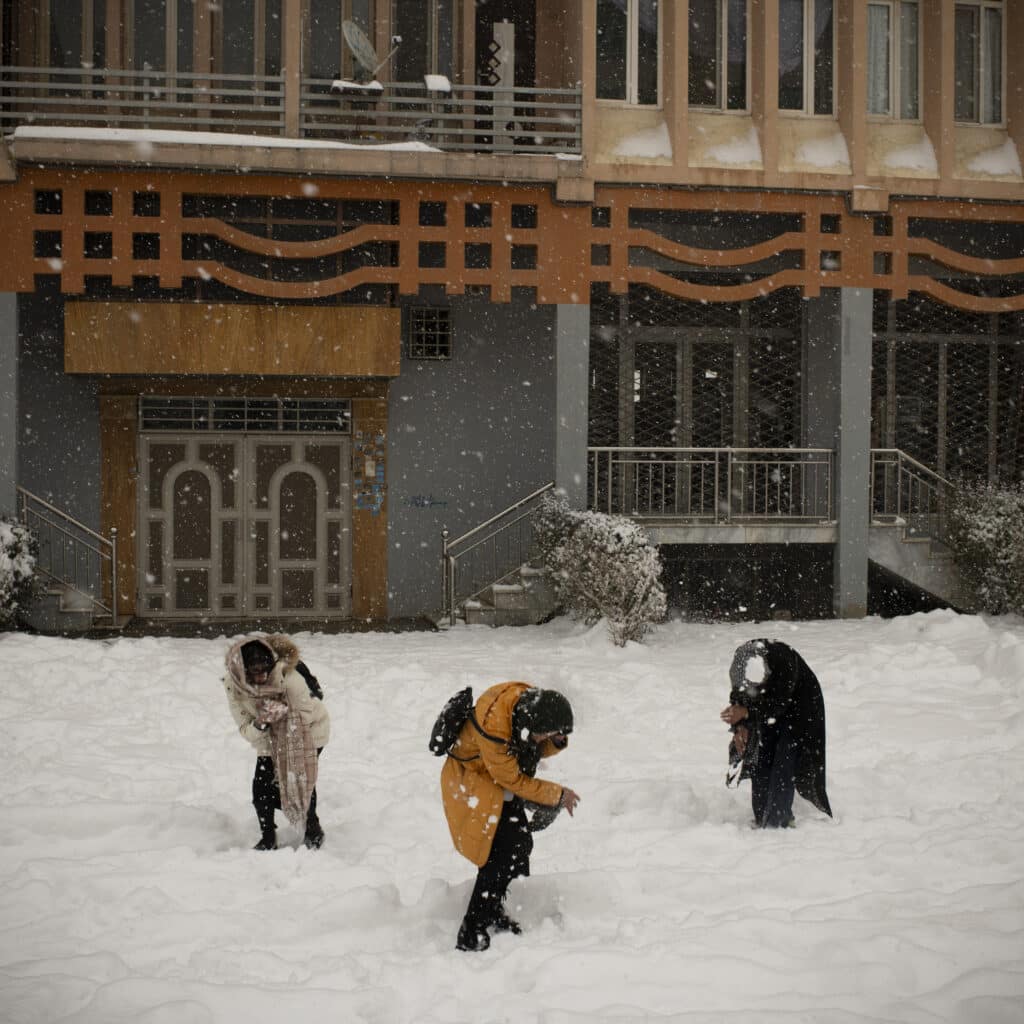 Kabul, Kabul, Afghanistan, February 3, 2024. Girls playing in the snow in western Kabul behind an apartment block, off the main road. Since the takeover, women and girls' rights to move without a male chaperon or to go to parks have been curtailed, and very few opportunities to find joy in their daily lives remain. A snowstorm in a quiet neighbourhood of Kabul western suburb offered such a chance for an hour of playing together. Even then, an eye is always kept on the surroundings, looking for a sign of a Taliban patrol. © Kiana Hayeri for Fondation Carmignac