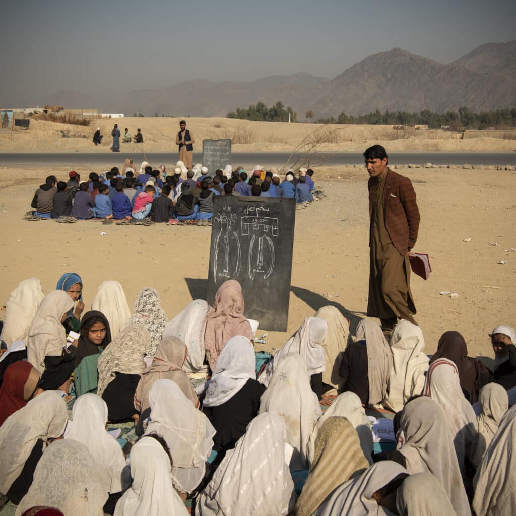 Gardi, Ghos district, Nangarhar, Afghanistan, February 13, 2024. In the absence of school buildings in Gardi Ghos District, classes are set up for students, between two main roads under the sun and on dirt ground. While boys can complete their education all the way to grade 12, classes were held for girls only until grade 6. As of today, girls are only allowed to study until grade 6, and are barred from both high schools and universities. In some districts, locally decided by authorities, girls are barred from school above grade 3. However underground schools set up at homes, mosques or alternative spaces continue educating girls, at a high risk. © Kiana Hayeri for Fondation Carmignac