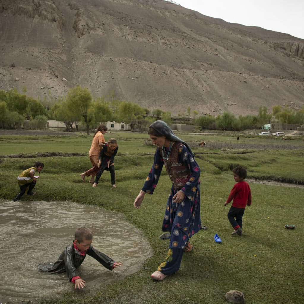 Yamit District, Badakhshan, Afghanistan, May 10, 2024. Kheshroo's daughter and her cousin, both grade 11 students who were put out of school, committed suicide a year before by throwing themselves in the water. The family plays in puddles of water, among troops of yaks, horses and goats, in front of the Wakhan mountains, Wakhan, a region that had never been controlled by the Taliban before 2021. © Kiana Hayeri for Fondation Carmignac