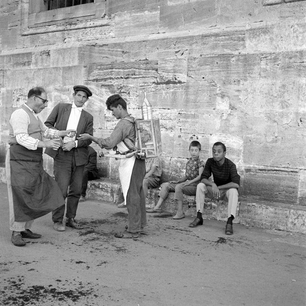 Sherbet seller, customers, and Baldwin at Yeni Cami (New Mosque), Istanbul, 1964 or 1965. © Sedat Pakay