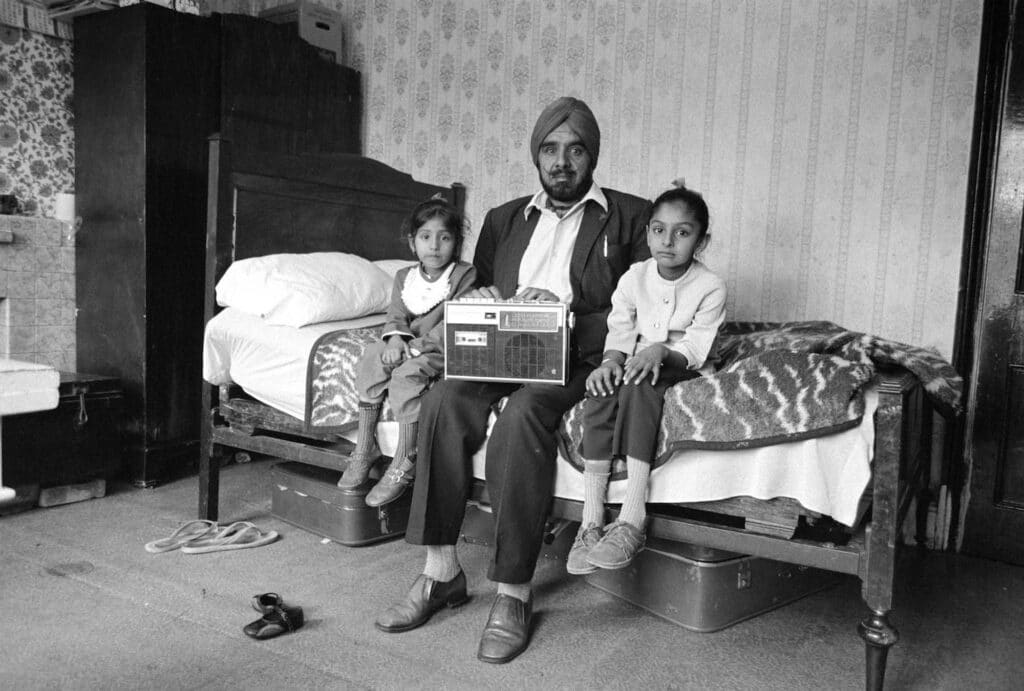 Dennis Morris, Man with his two daughters and his most prized possession, Southall, 1976 © Dennis Morris